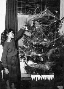 878185 Portret van Wil Klein bij een opgetuigde kerstboom in de huiskamer van de slagerij annex woning Oranjestraat 6 ...